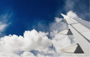 Blick aus dem Fenster eines fliegenden Flugzeugs mit Sich auf Tragfläche und blauem Himmel